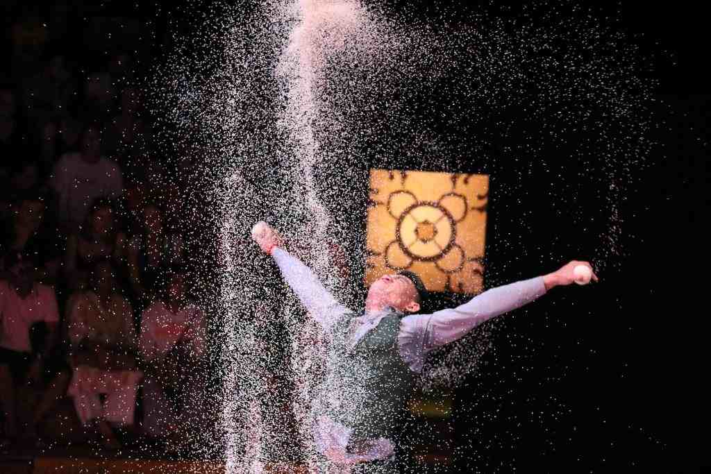 Phare Circus performance "White Gold"- male artist juggling under shower of rice in Cambodia